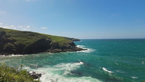 View-looking-down-on-sea-and-coastline,-foliage-in-foreground,-sunny-day