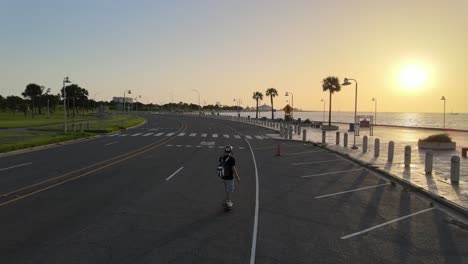 tracking shot of an active man riding electronic skateboard at lakeshore drive on sunset in new orleans, louisiana usa