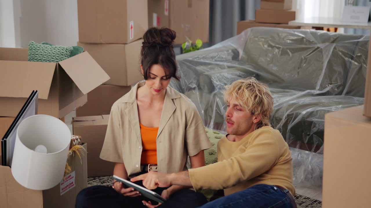 Young Couple Planning New Home Decor with Tablet Amidst Moving Boxes