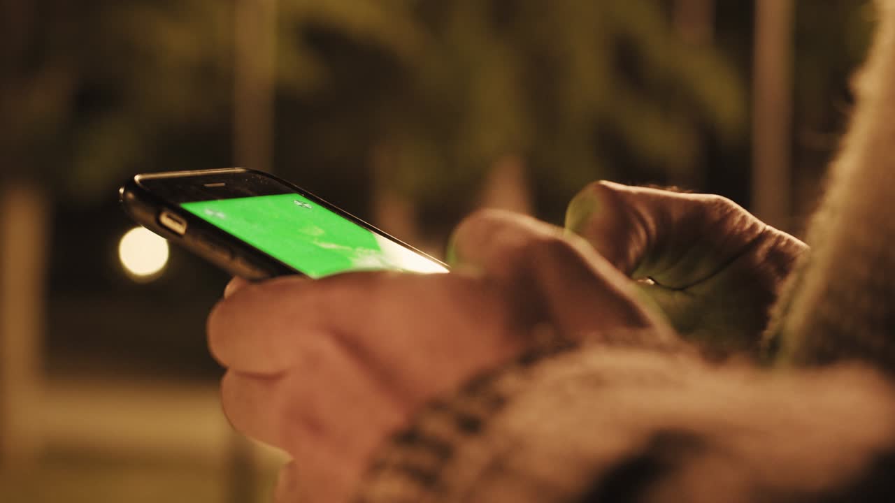 vista posteriore di un uomo che tiene in mano uno smartphone con schermo verde
