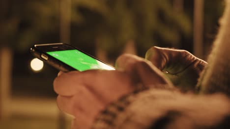 back view of man holding smart phone with green screen