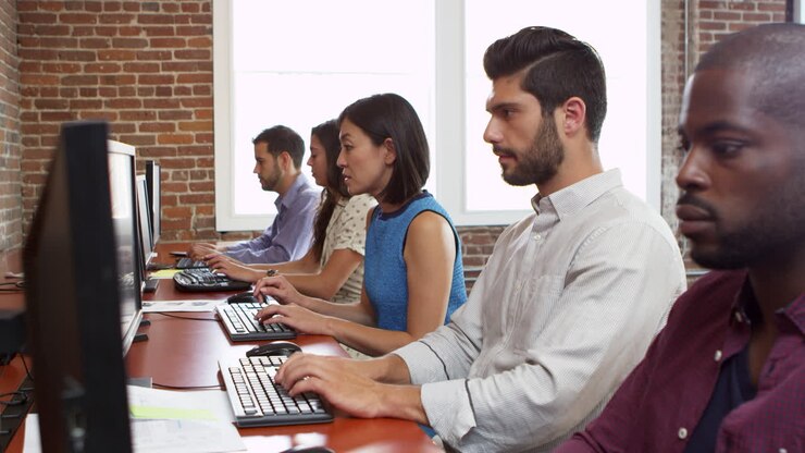 Staff Use Computers Sitting At Desks In Office Shot On R3D