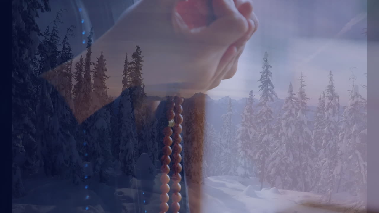 Holding prayer beads, hands in snowy forest, contemplating serene winter landscape