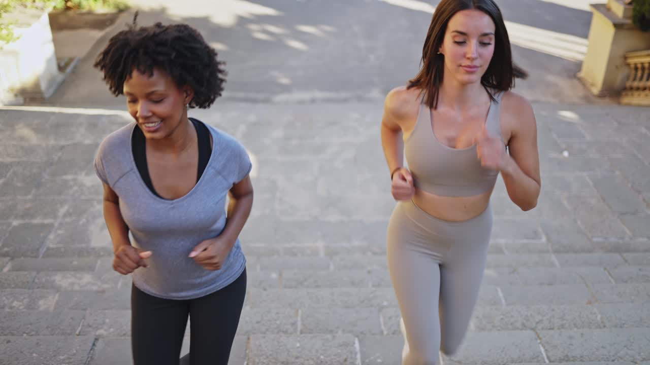 Due donne diverse che salgono le scale all'aperto correndo durante l'allenamento