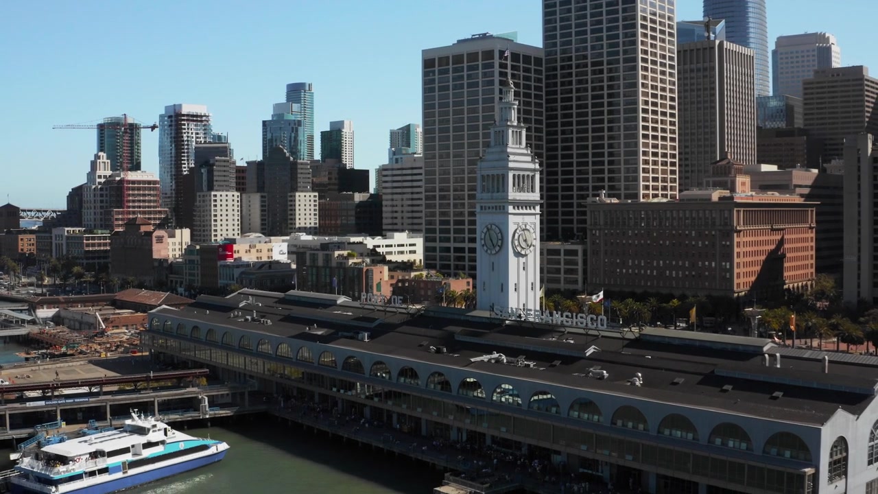 Ripresa aerea con drone che si allontana rivelando l'iconico Ferry Building di San Francisco e lo skyline del lungomare del centro - (UHD 4K)