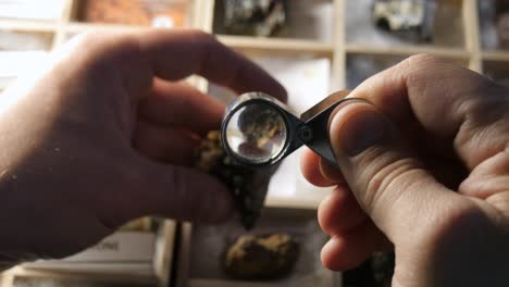 geologist hand looking at rock mineral crystal collection