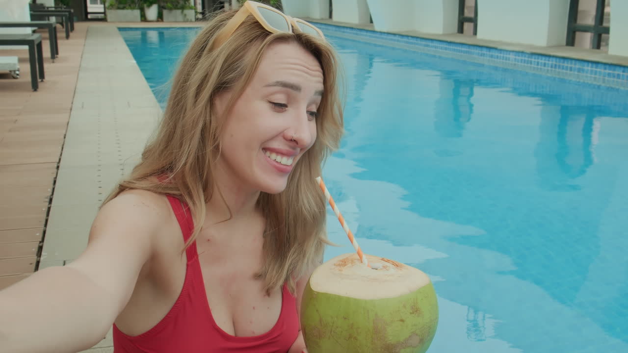 Female Tourist Sipping Coconut Drink by Poolside POV