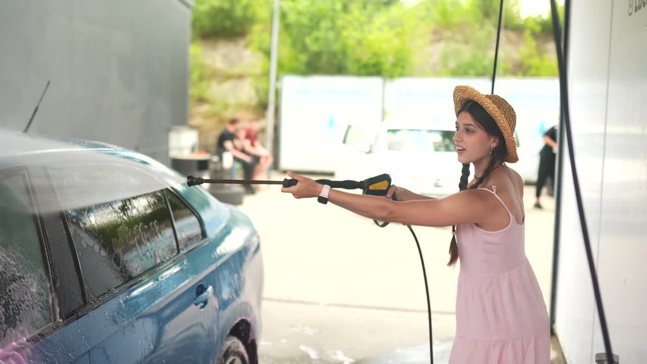 mujer lavando un coche en un lavado de coches de autoservicio