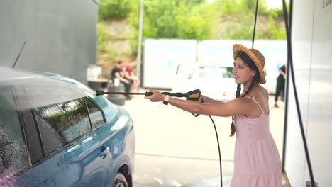 mujer lavando un coche en un lavado de coches de autoservicio