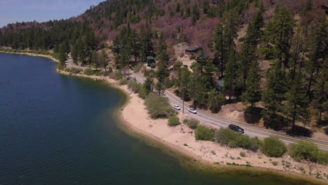 cars driving on the winding road on the edge of the big bear lake, california