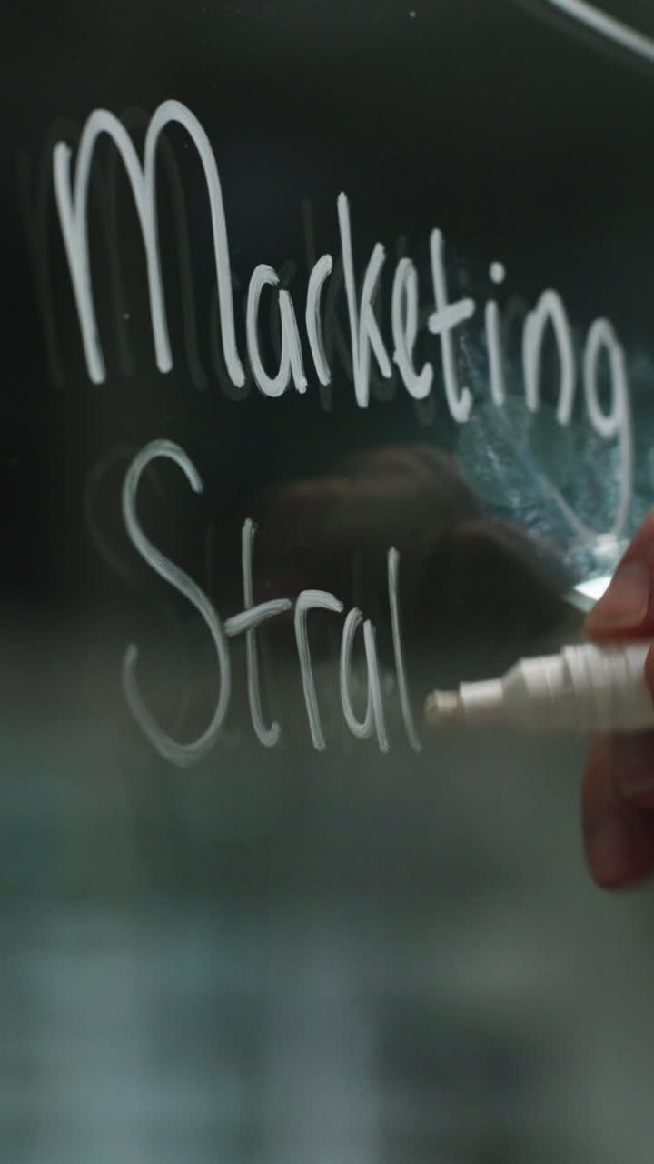 Ręka pisząca strategię marketingową na szklanej tablicy
