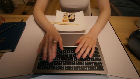 woman working at laptop with sushi