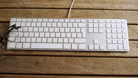 gafas y teclado en una mesa de madera 4k