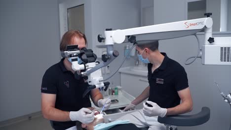 dentist looking into microscope. dentist treating patient, using microscope at the dental clinic