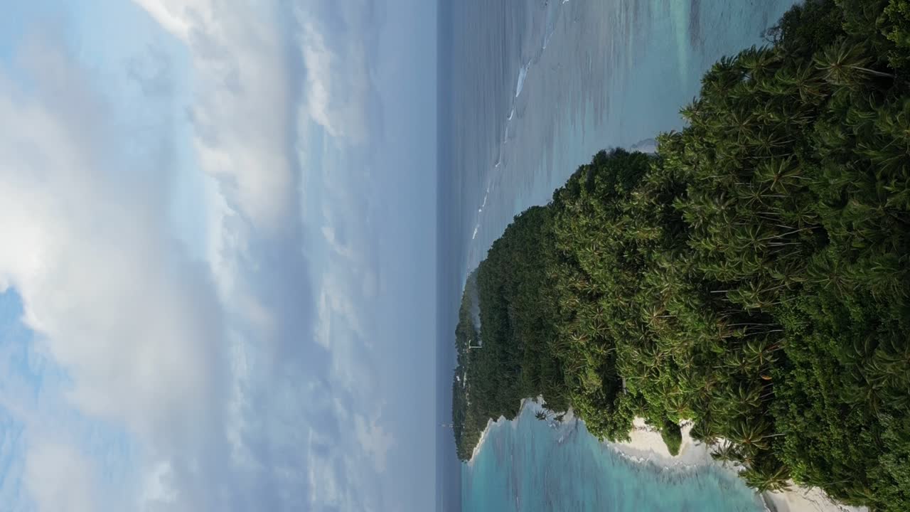 Lunga e stretta lingua di sabbia bianca dell'isola di Dhigurah, Maldive, coperta da una lussureggiante vegetazione tropicale e palme da cocco.