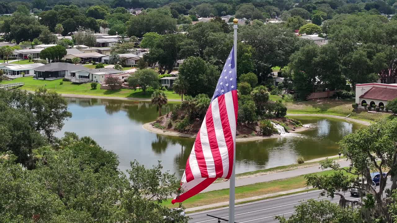 bandera estadounidense ondeando frente a los pueblos vecindario con el lago en florida