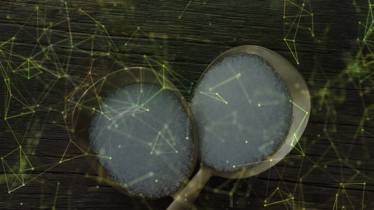 Brass spoons holding white coarse granules, resting on wooden surface, showing green data network
