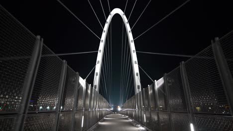 Tilt-down-wide-shot-of-Urban-city-metal-suspension-walking-bridge-at-night