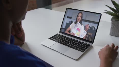 Mid-section-of-african-american-woman-having-a-video-call-on-laptop-with-female-colleague-at-office