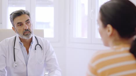 doctor listening to a female patient in a clinic