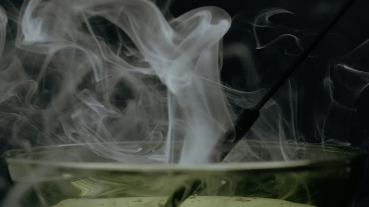 A smoky relaxing scene with a bowl of essence burning on a stick , making soft calm waves of smoke