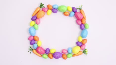 happy easter write in frame made of vibrant eggs on white background. stop motion flat lay
