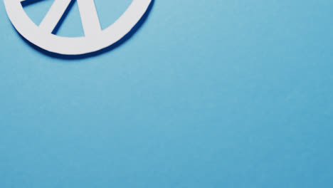 Close-up-of-white-peace-sign-and-copy-space-on-blue-background