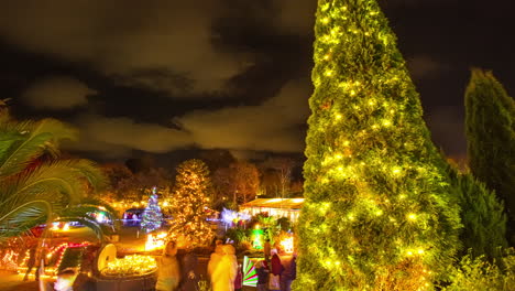 public park decorated by colorful christmas lights at night with people strolling around enjoying the view, guernsey island