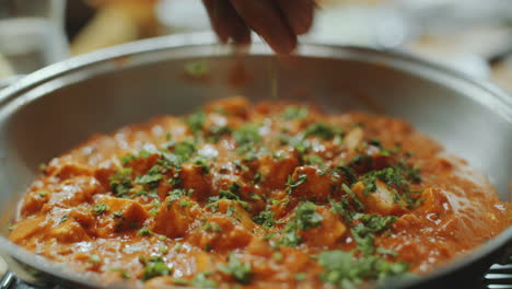 close-up of garnishing paneer butter masala with fresh coriander