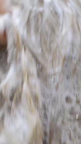 a young woman washes her hair with shampoo on white tiles background.