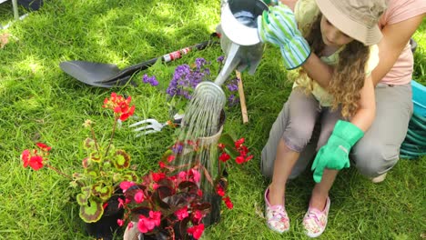 cute little girl watering flowers with her mother