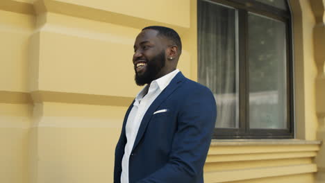 african businessman walking on urban street. cheerful afro man checking time.