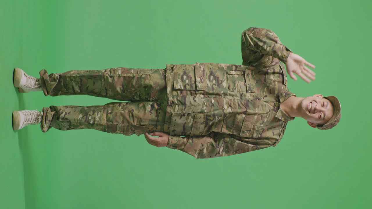 Full Body Of Asian Man Soldier Smiling, Waving Hand, And Saying Bye While Standing In The Green Screen Background Studio