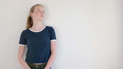 caucasian woman in navy blue t shirt with white edging, against white wall, copy space, slow motion