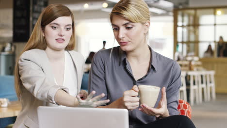 business women meeting in cafe using laptop drinking coffee