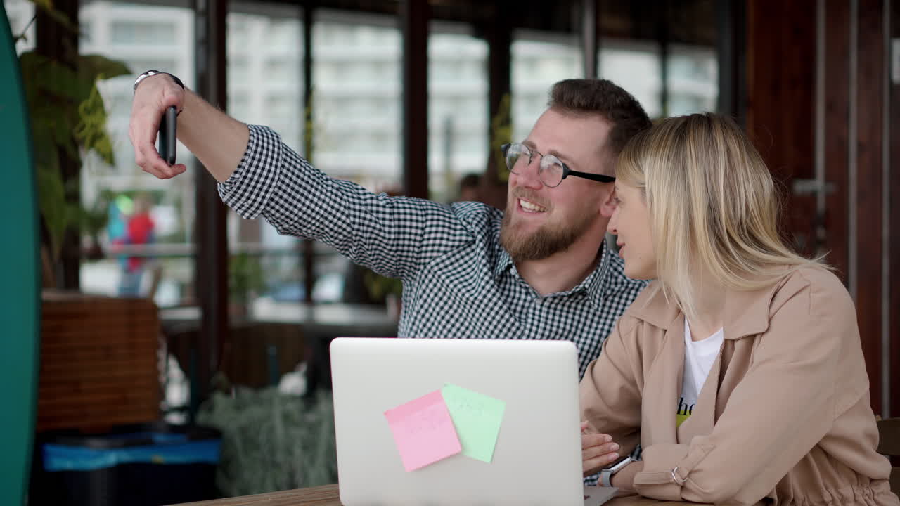 una pareja tomando una selfie en un café.