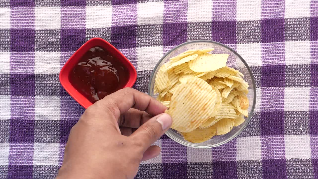 mano sosteniendo un chip con salsa de tomate