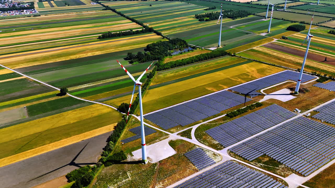 Wind and solar energy fields. Vibrant farmland hosts wind turbines and solar panels, highlighting sustainable energy practices under a clear sky
