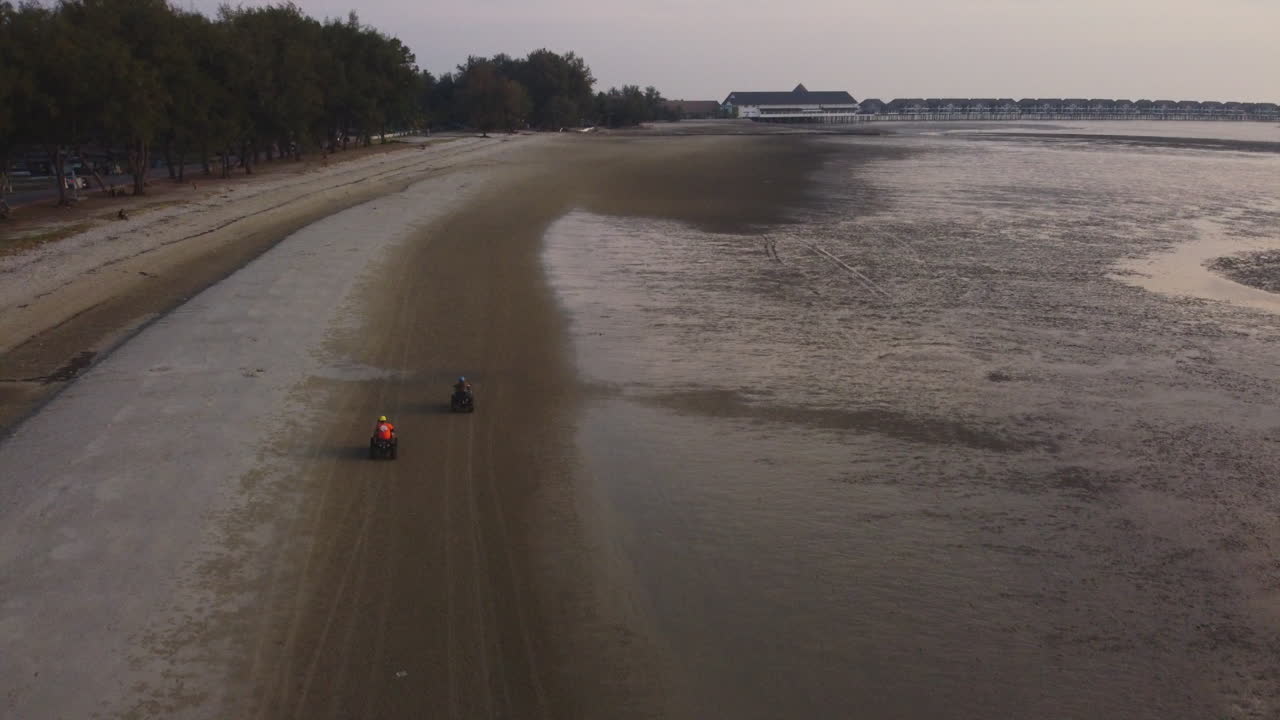 вид с дрона за гонщиком на квадроцикле на пляже в багане лаланг, малайзия