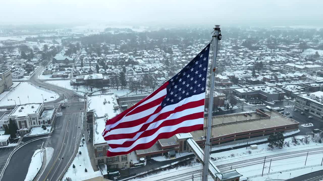 Primo piano aereo della bandiera americana che sventola su un paesaggio suburbano innevato