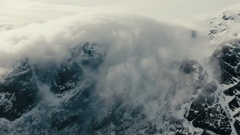 aerial view of mountain peaks shrouded by thick fog and clouds in winter in lofoten, norway.
