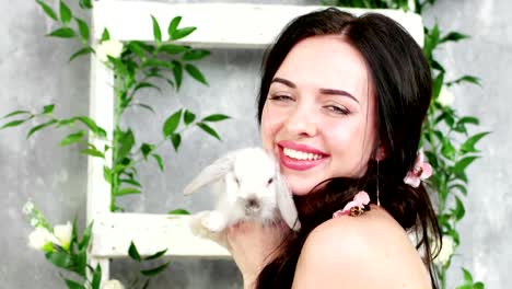 closeup portrait of happy smiling woman holding white cute long-eared rabbit, spring photo session