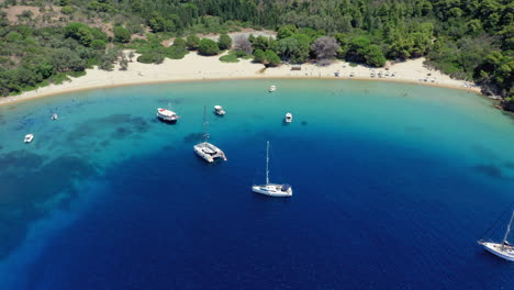 aerial: panoramic shot of tsougria island beach near skiathos, sporades, greece with moored sailboats and catamarans