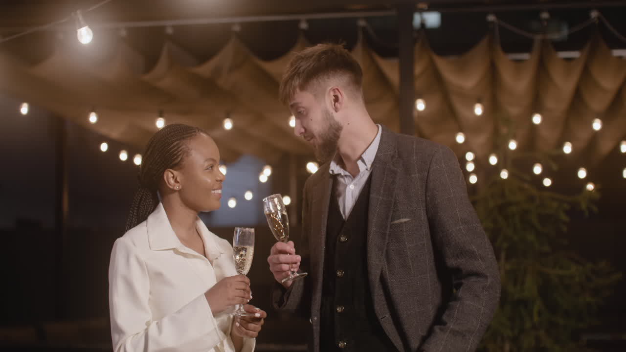 Uomo e Donna che brindano con calici di champagne mentre si riprendono in un video selfie alla festa di Capodanno