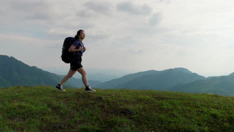 solo traveller woman hiking a mountains path with amazing landscape, backpacker trekking trip in slow motion