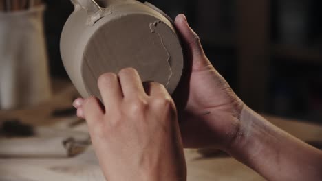 woman potter chipping away the wet excess of the clay from the bottom of a cup