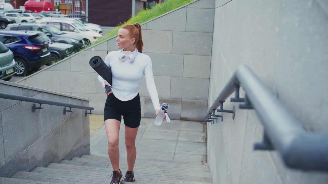 Woman with yoga mat on stairs
