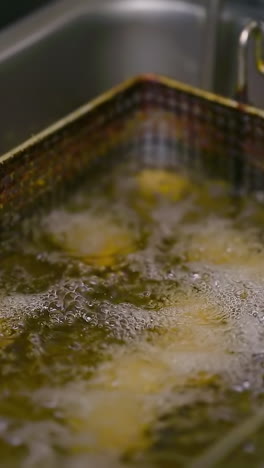 fries in the deep fryer. chef cooking in modern kitchen of restaurant