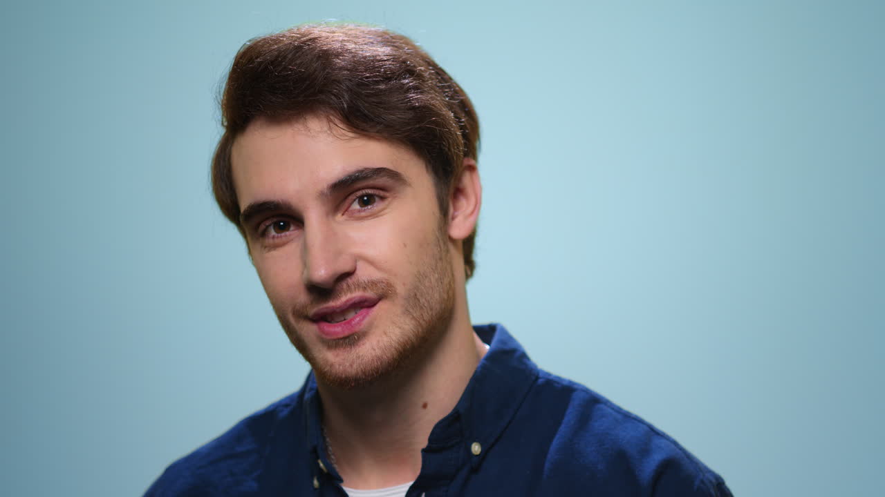 Handsome man sending air kiss to camera. Bearded guy flirting on blue background