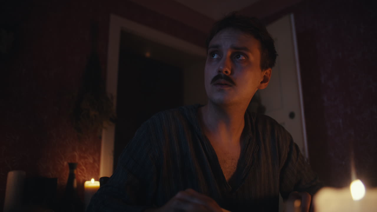 A Man Contemplating in a Candlelit Room